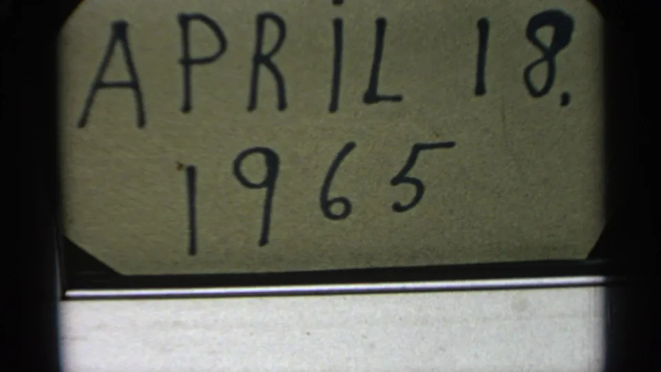 Handwritten April 18, 1965 date card fills the upper frame, with a subdued water view below in 8mm home-movie footage.