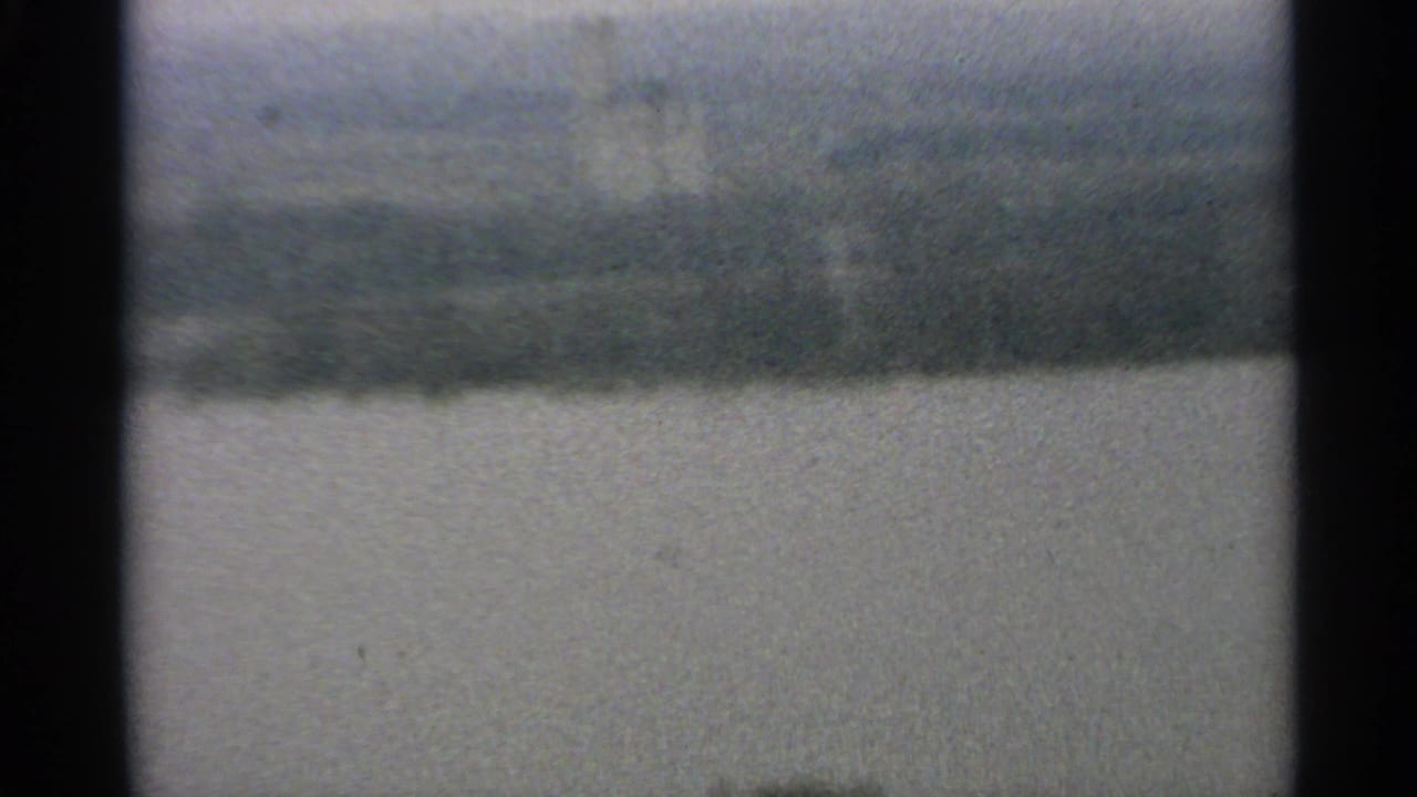 1965 Minnesota 8mm frame showing a soft, hazy view across open water toward a distant wooded shoreline.