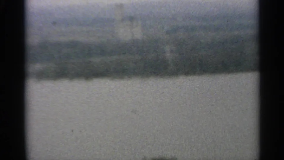 1965 Minnesota 8mm frame showing a soft, hazy view across open water toward a distant wooded shoreline.