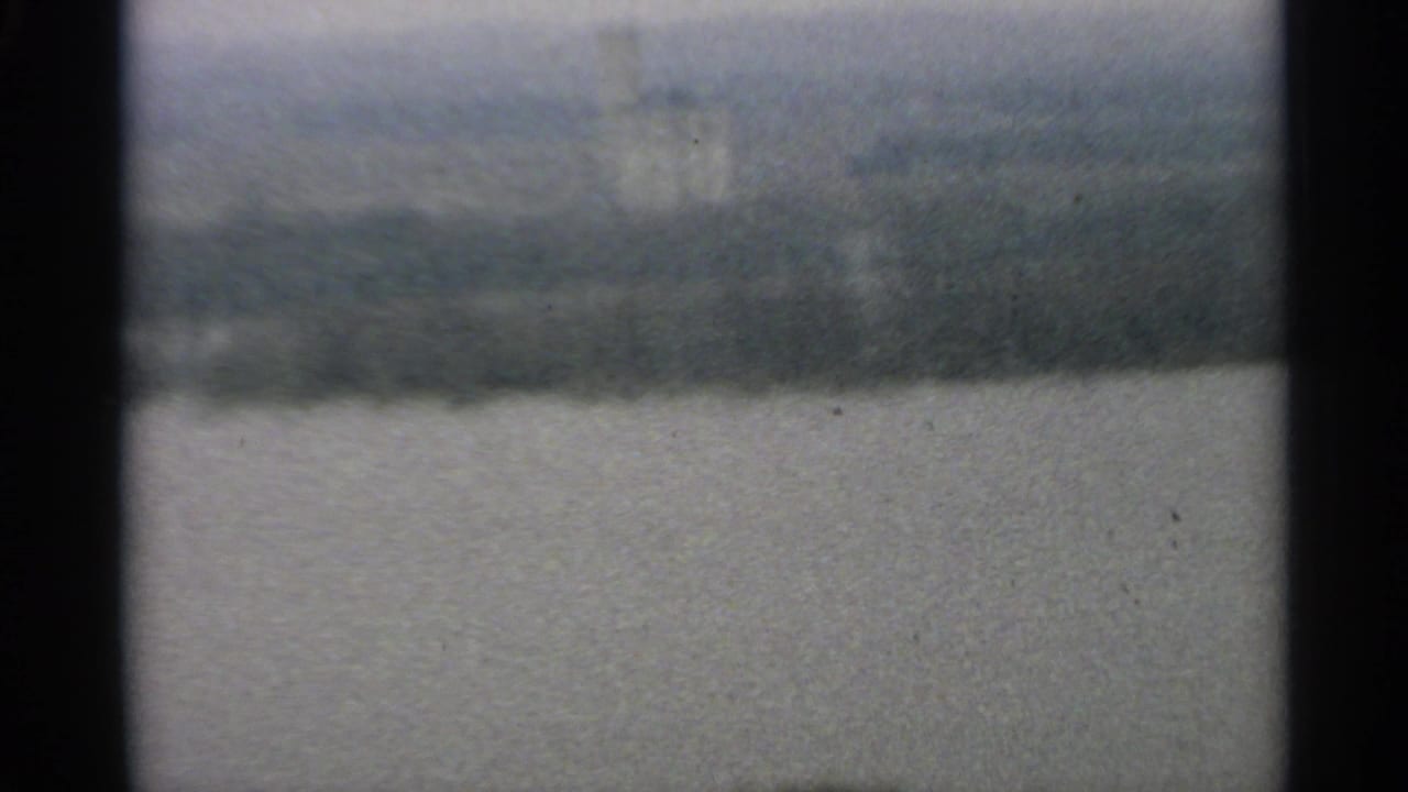 Soft view over water with a blurred far shore and pale sky.