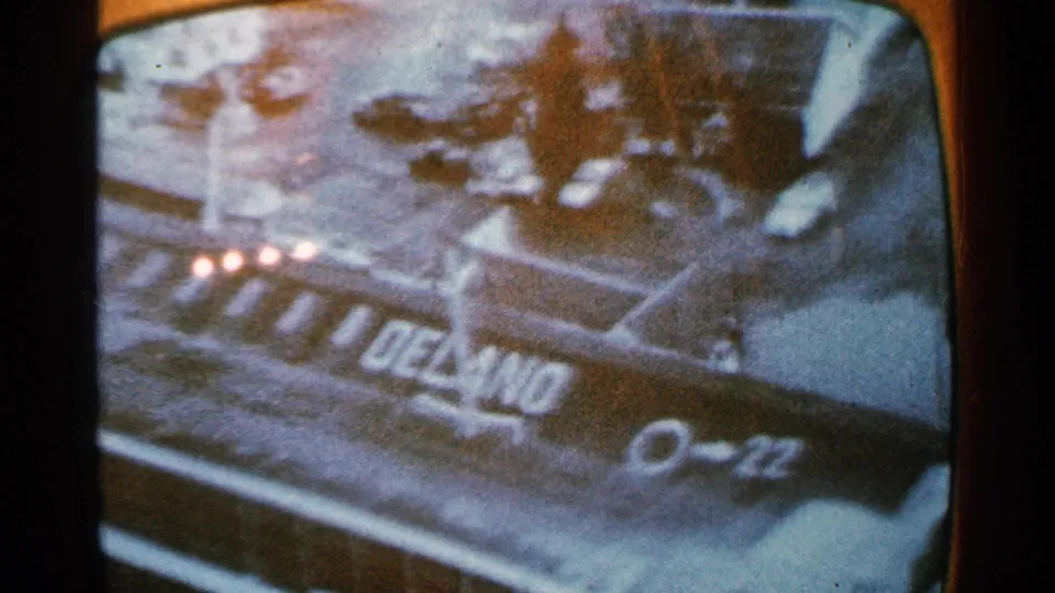 1965 8mm Minnesota frame showing a snowy overhead view with a large DELAND marking, 0-22, and nearby dark shapes.