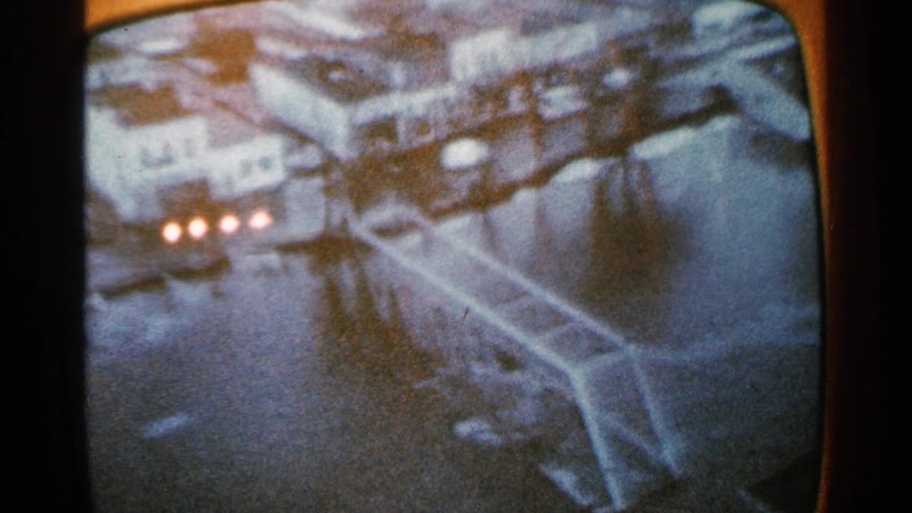 Oblique aerial view of floodwater, buildings, and a bridge-like structure.