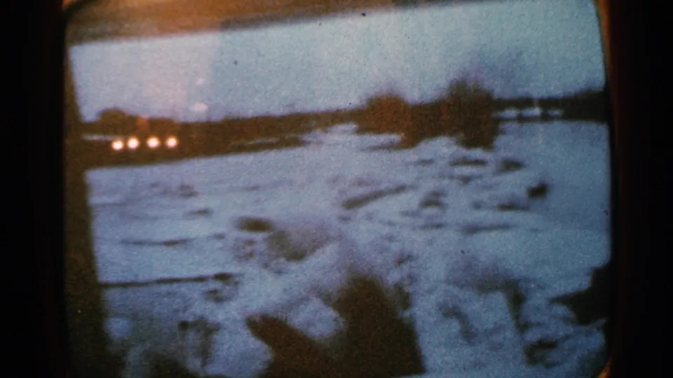 Minnesota 1965 frame showing a wider flooded area with pale snow or debris, dark structures and distant points of light.