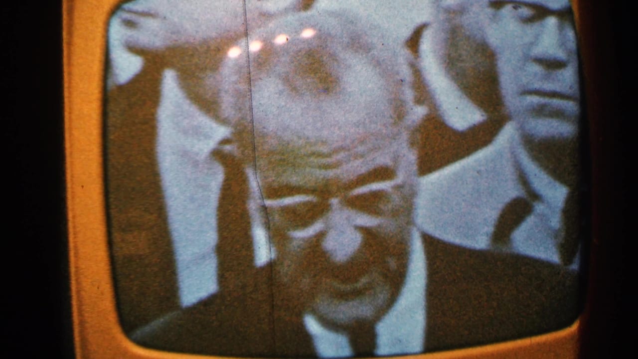 Old television screen with a close view of a suited man in a broadcast crowd.