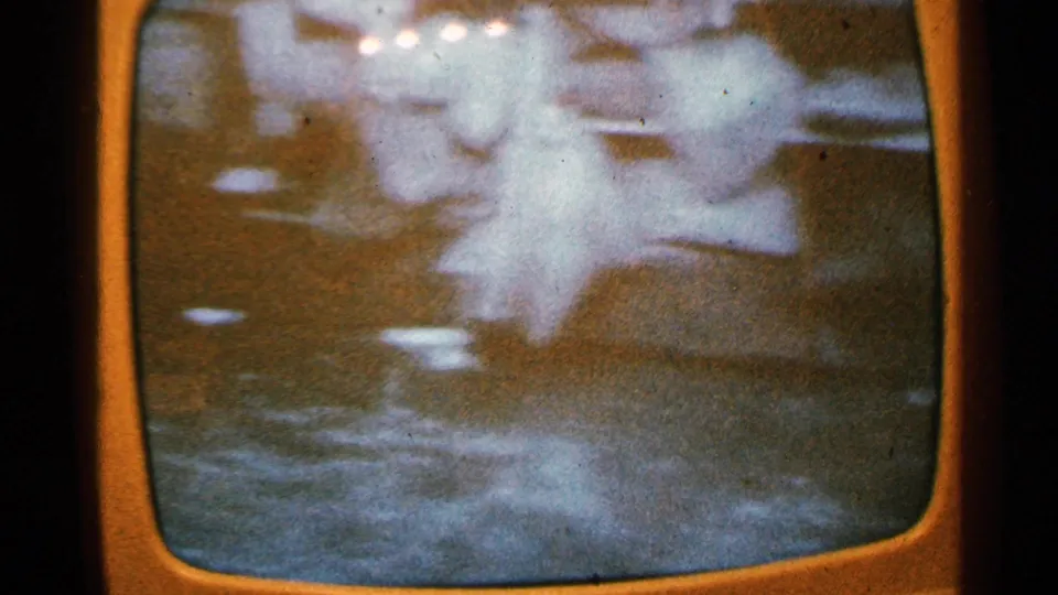 Minnesota 1965 home-movie frame showing a blurred old television broadcast image with abstract motion, glare, and scan-line distortion.