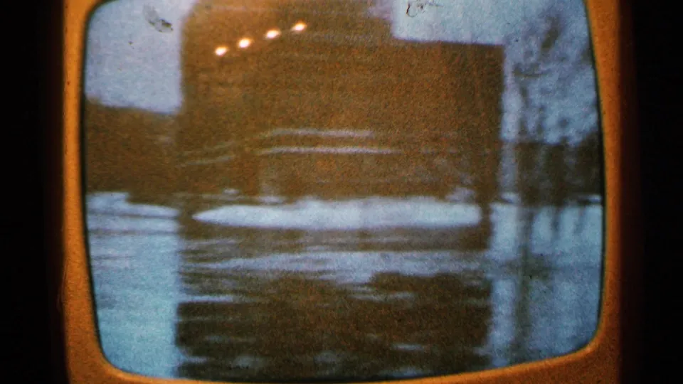 The 8mm frame records a small TV view of water covering the foreground near a dark structure or bank.