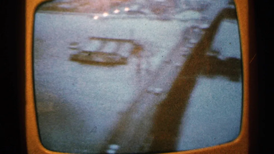 Minnesota 1965 frame appears to show a bridge over water, viewed in motion with blue-orange color shift and heavy grain.