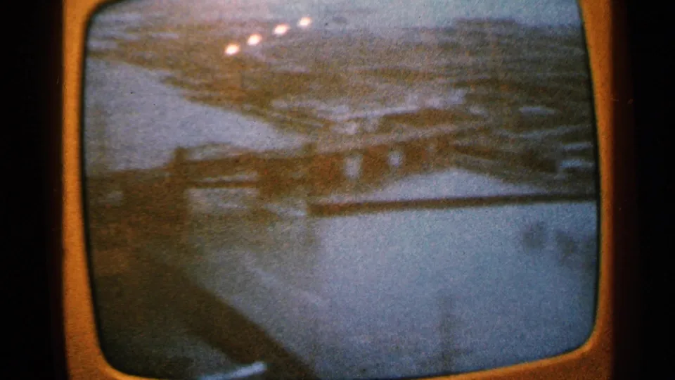 Minnesota 1965 frame appears to show an angled bridge or roadway section beside water, with shoreline detail and strong film grain.