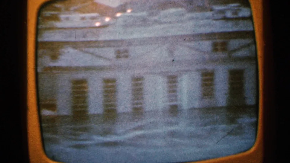 1965 Minnesota 8mm frame with a soft aerial view of a riverside building or industrial structure near water, transferred through a screen.