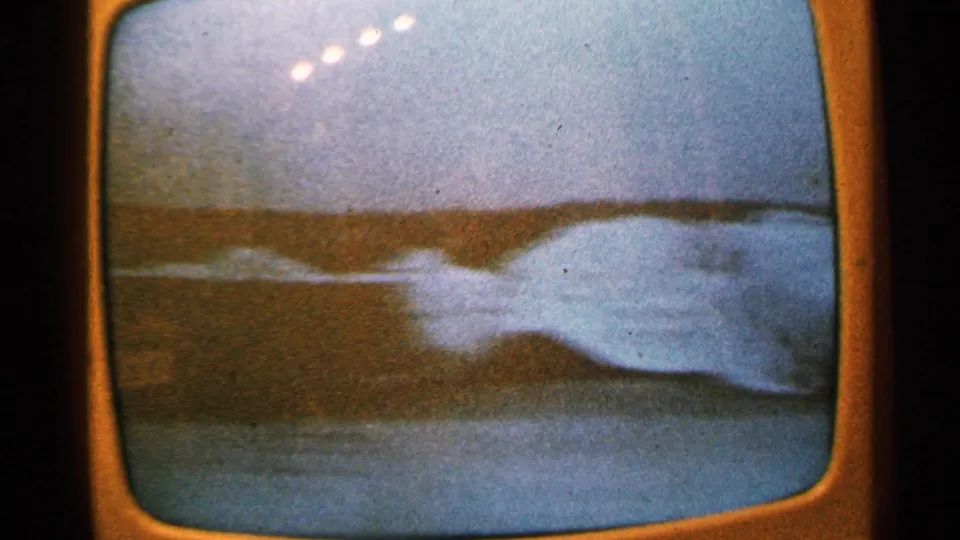 1965 Minnesota filmed television frame showing a bright area of floodwater against a darker shoreline or street edge.