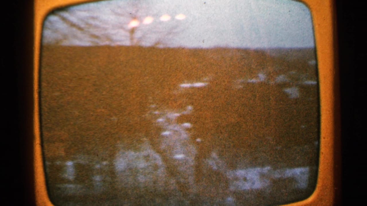 Television screen showing a wide field with distant pale shapes.