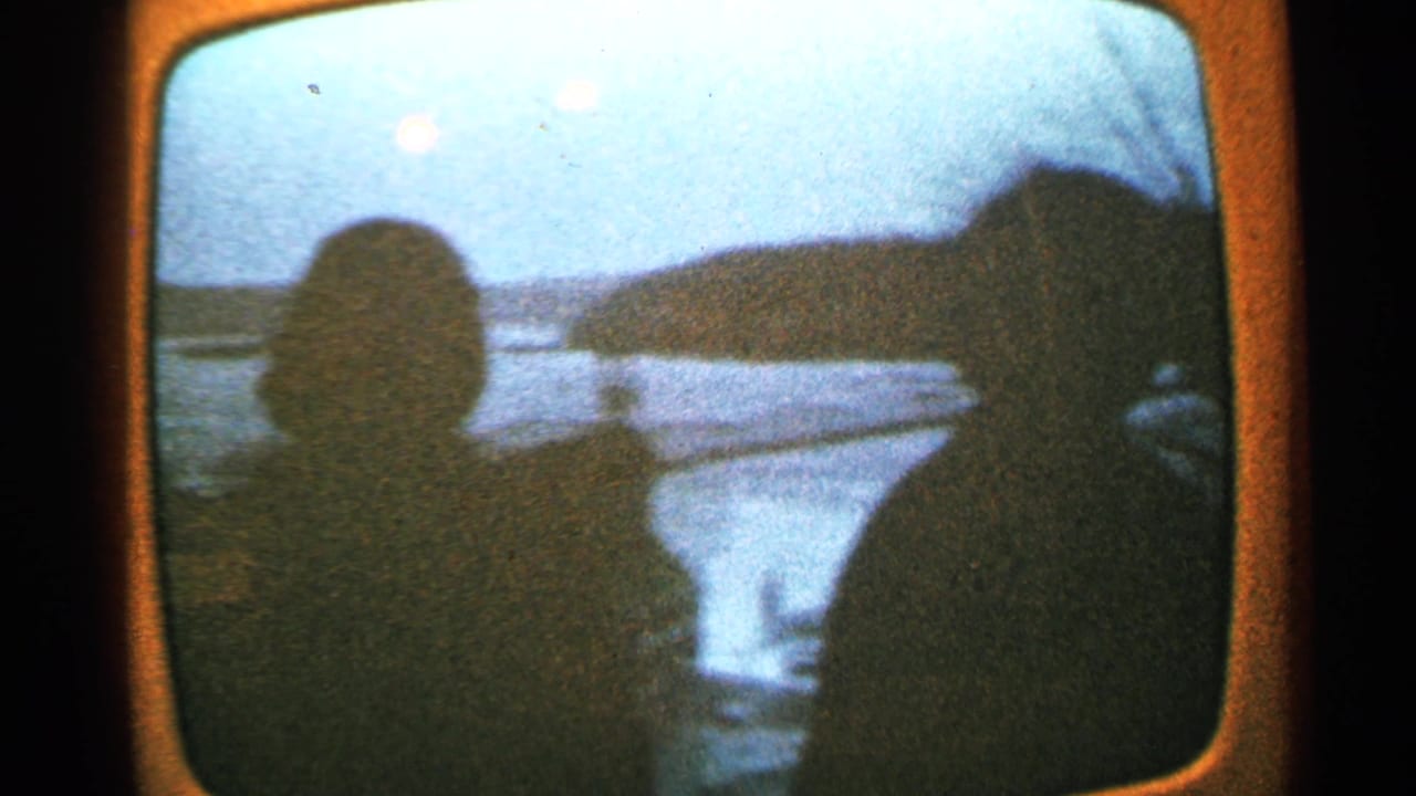 Two silhouetted people sit facing a body of water on a rounded screen.