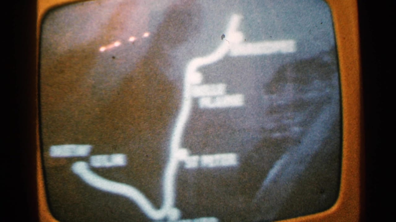 1965 Minnesota home-movie frame of a rounded television screen displaying a grainy route map with indistinct destination labels.