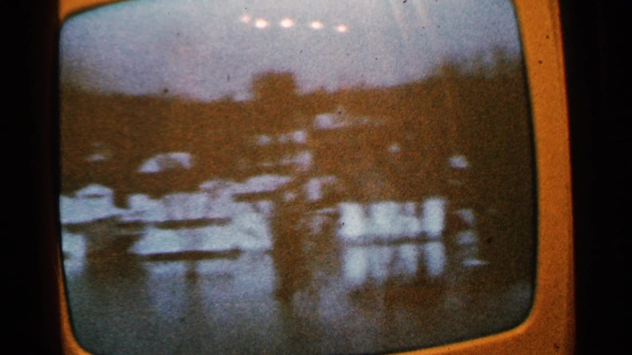1965 Minnesota frame showing a soft televised or filmed lakeside scene with trees, buildings, water, and reflections.
