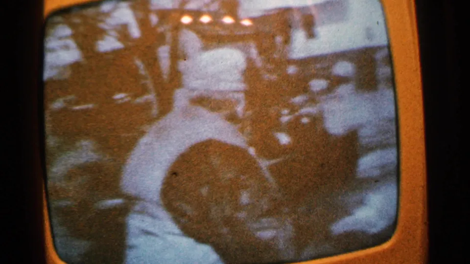 1965 Minnesota 8mm frame showing a man in a light shirt near possible boats or shoreline, with a visible face low in the frame.