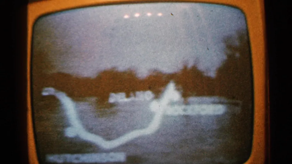 Grainy 8mm view of a Minnesota television flood report, with a white waterway outline and bright broadcast highlight.