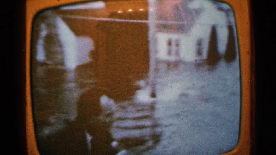 1965 Minnesota home-movie frame of a TV report showing houses partly surrounded by flood water.
