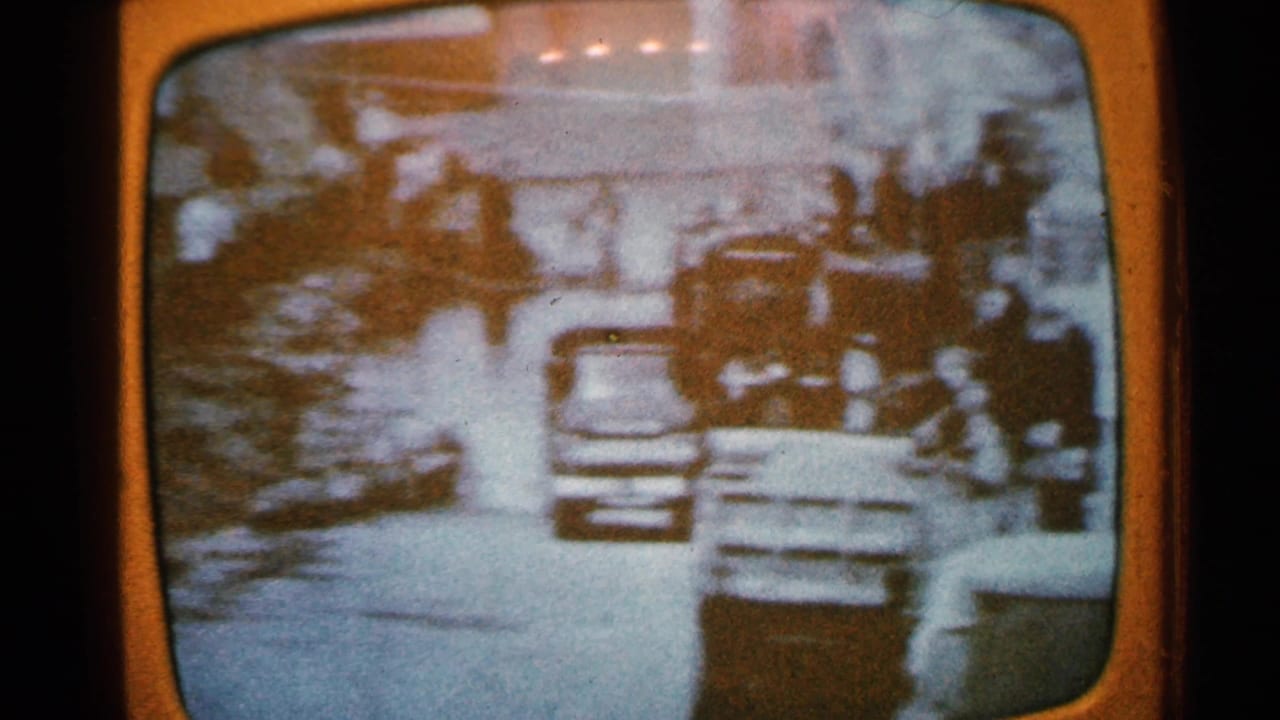 Flooded residential street with cars, people, and water covering the road.