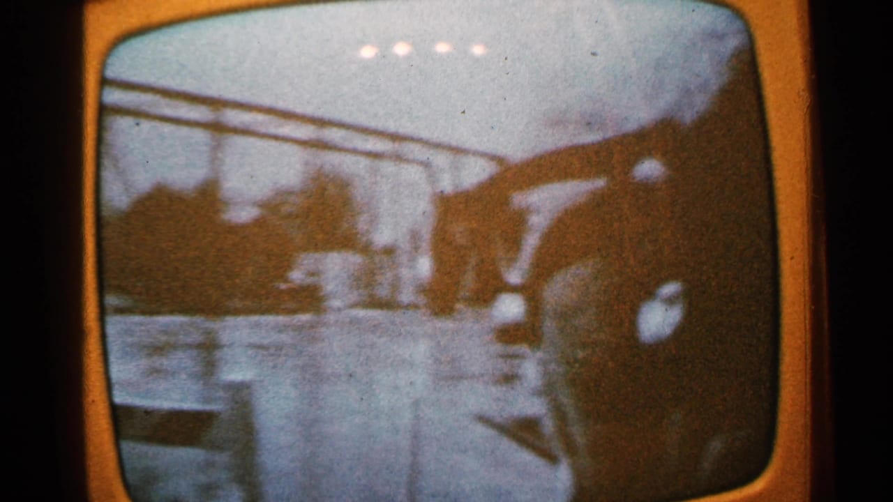 Grainy 1965 Minnesota television broadcast footage shows a flooded street with a vehicle, overhead lines, and a distant helicopter-like shape.