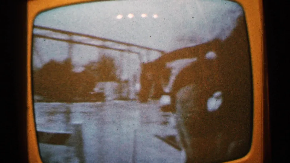 Grainy 1965 Minnesota television broadcast footage shows a flooded street with a vehicle, overhead lines, and a distant helicopter-like shape.
