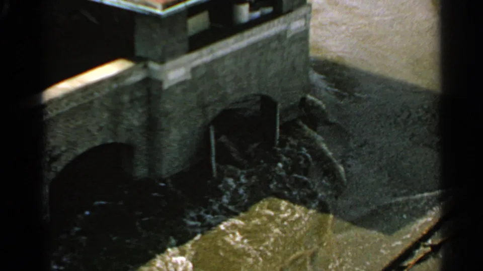 Close view of fast-moving water flowing through masonry arches, likely part of the same Minnesota waterfront sequence.