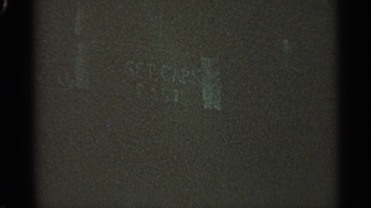 Mostly dark film frame with faint edge marks and little visible scene detail.