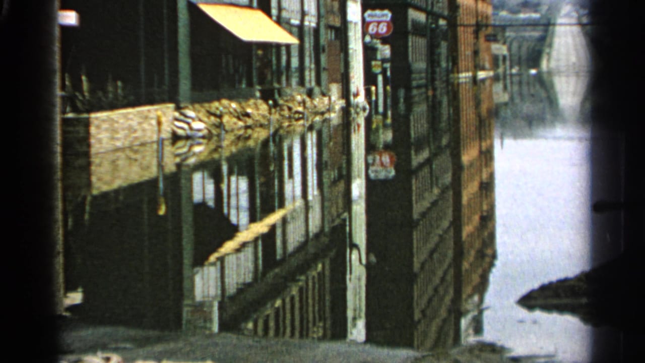 Flooded commercial street with storefront reflections and vertical roadside signs.