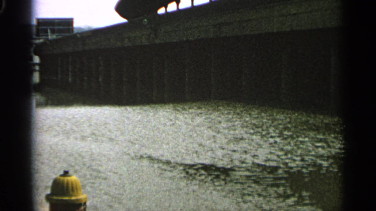 Rippling water under a dark bridge or wall with the fire hydrant still partly visible.