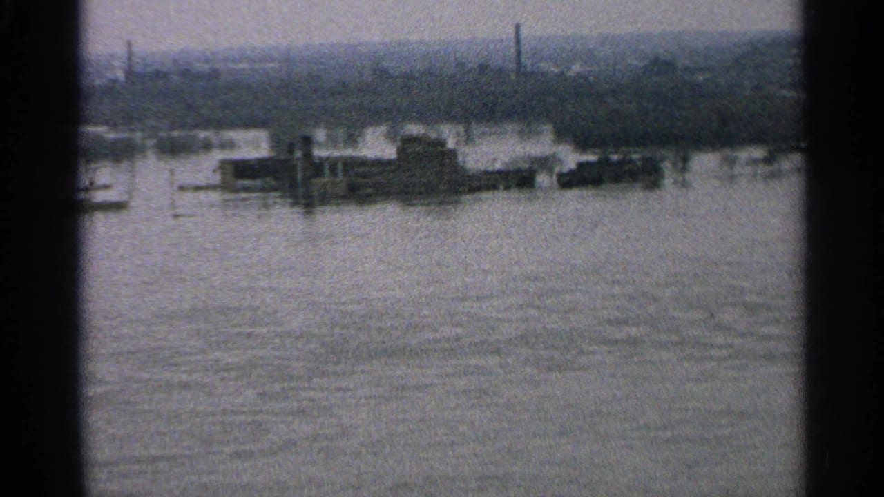 1965 Minnesota home-movie view of a flooded suburban waterfront, with structures partly surrounded by water.