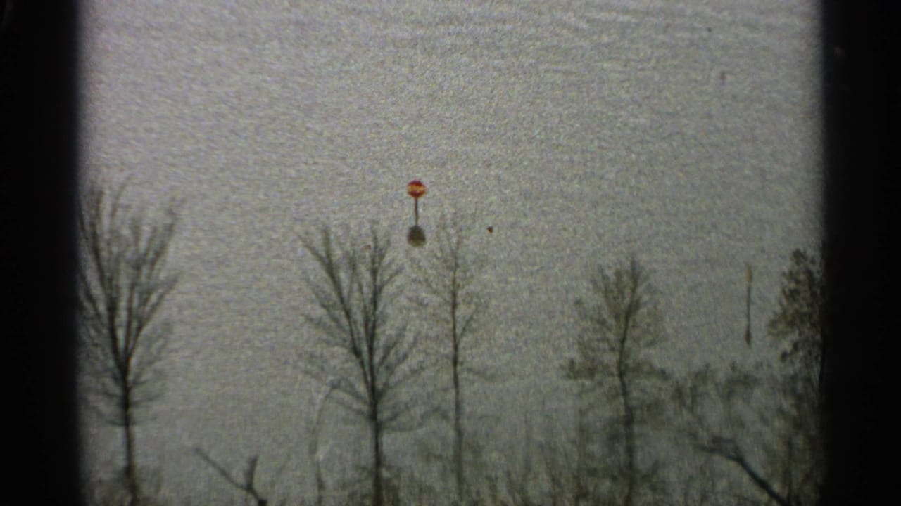 Bare winter trees and ski-lift poles seen through dark 8mm film edges.