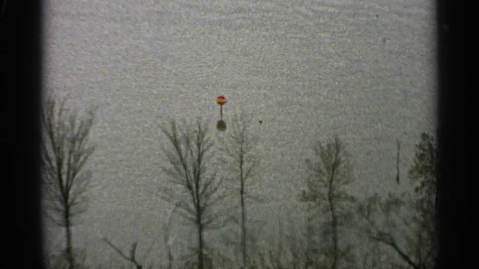 1965 Minnesota 8mm frame with bare trees, ski-lift poles, overcast sky, and visible film-gate borders.