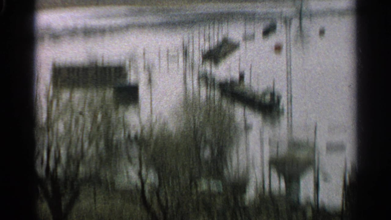 Soft, blurred 1965 Minnesota flood view with boats and docks partly surrounded by high water.