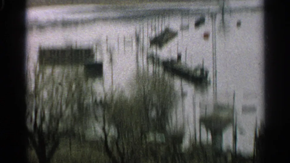 Soft, blurred 1965 Minnesota flood view with boats and docks partly surrounded by high water.