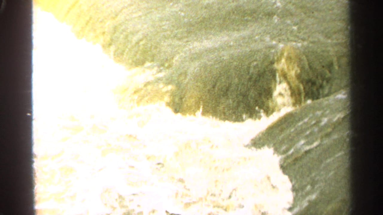 1965 Minnesota 8mm frame with foamy water rushing through a concrete dam or spillway structure.
