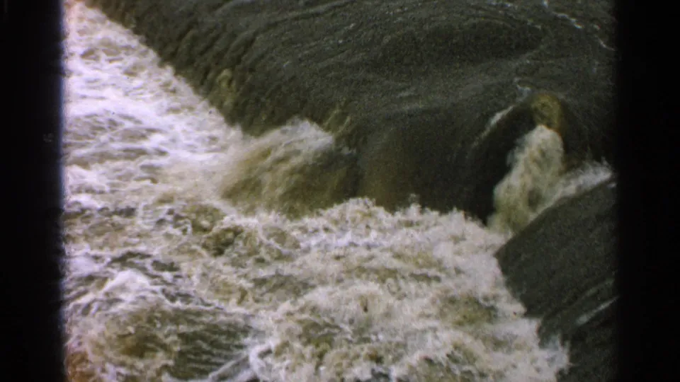 Close 8mm view of turbulent Minnesota water churning against dark concrete dam or spillway surfaces.