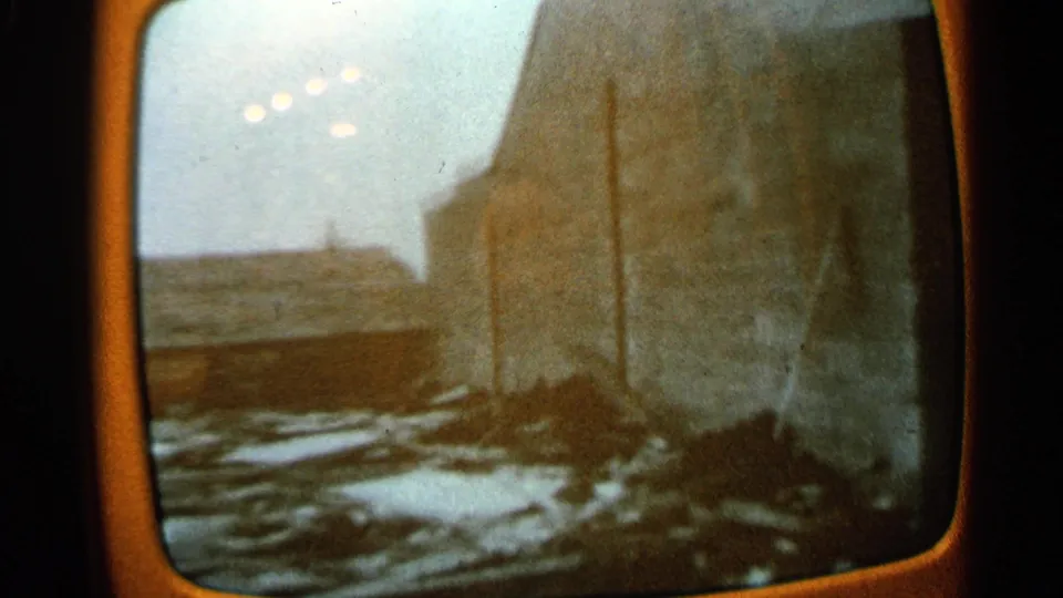1965 Minnesota 8mm frame of a television view with rubble along a large building wall and an overcast or washed-out sky.