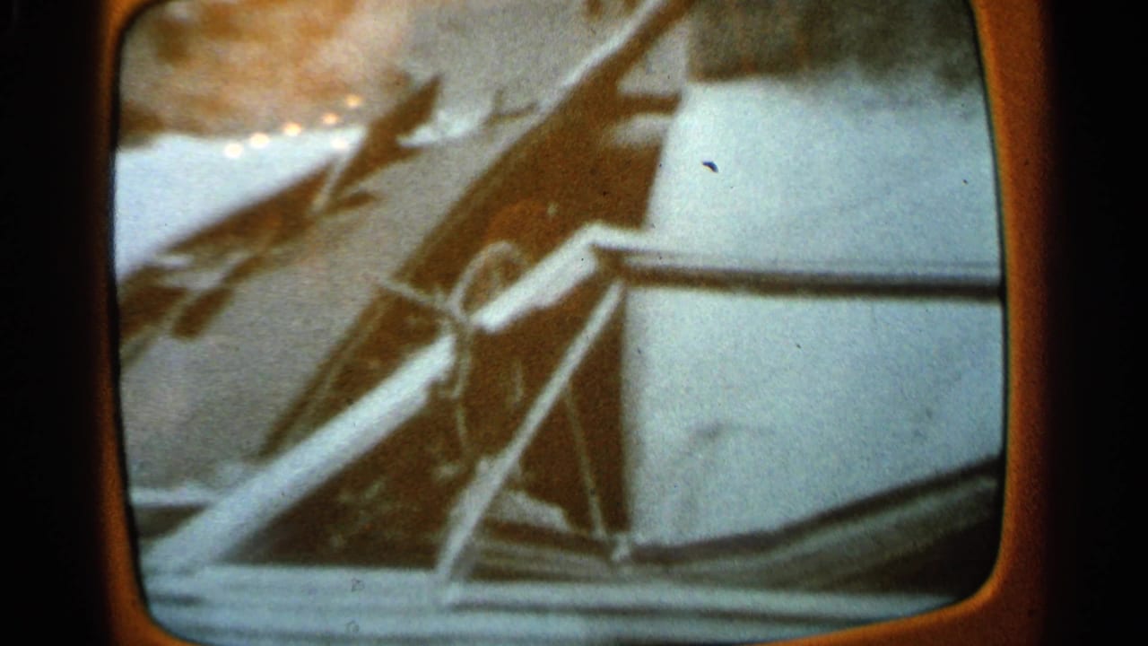 1965 Minnesota 8mm frame showing a wheel-like control and snowy exterior beyond the vehicle window.
