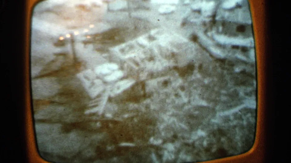 1965 Minnesota home-movie frame with a blurred snowy landscape, bare trees, and indistinct winter ground detail.
