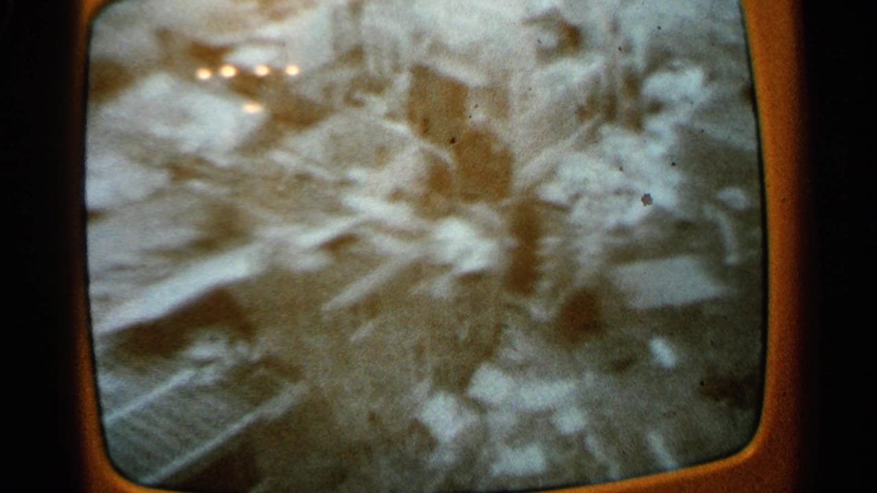Blurred television frame showing debris and possible cleanup activity after storm damage.