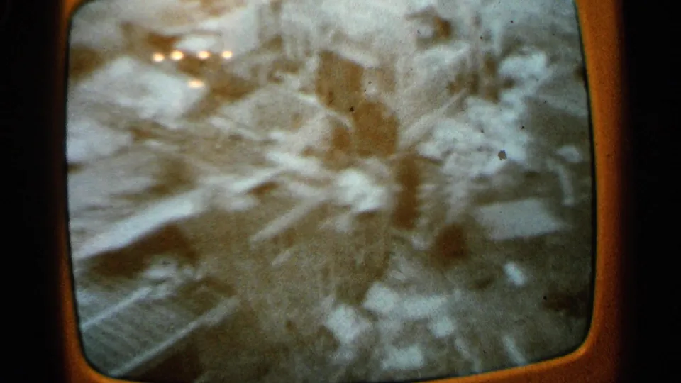 Grainy 1965 Minnesota home-movie view of a television broadcast showing debris-strewn tornado aftermath.