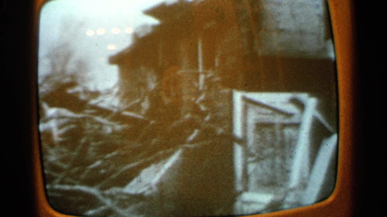 1965 Minnesota television broadcast captured on 8mm, showing damaged buildings and scattered debris after a tornado.