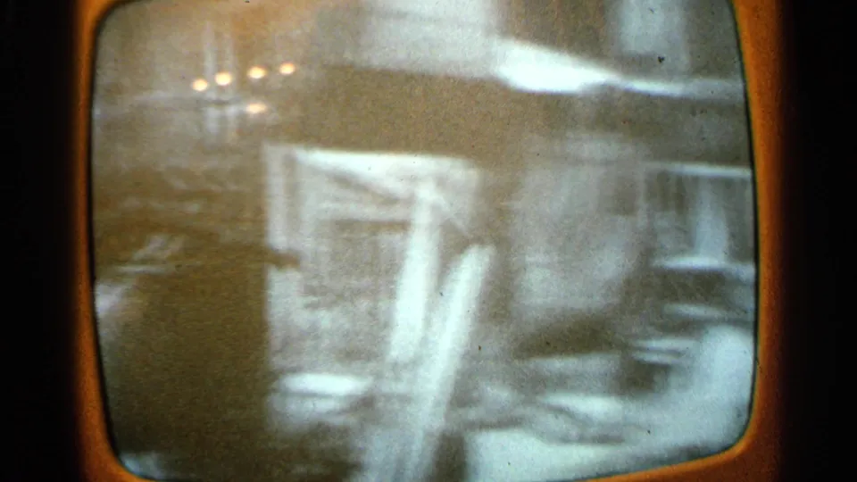Soft, grainy TV broadcast view of a damaged house exterior in Minnesota tornado aftermath footage from 1965.
