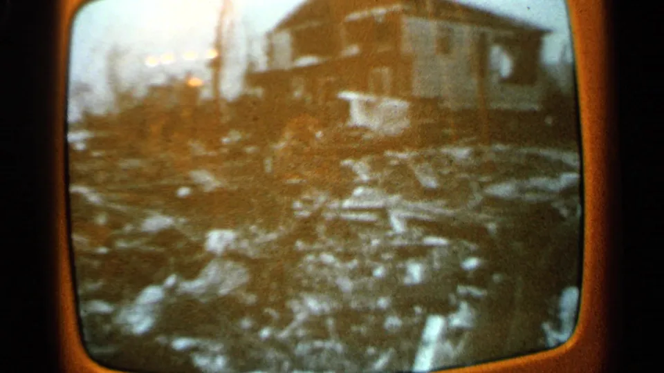 1965 Minnesota 8mm footage of a television screen showing storm damage around a house and scattered debris.