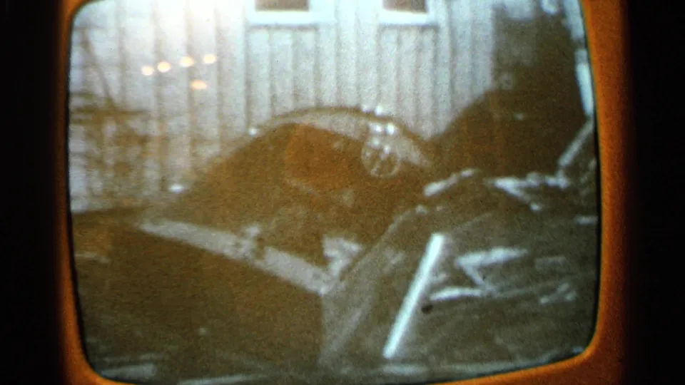 Re-filmed 1965 Minnesota TV footage showing a crushed vehicle near a damaged garage or outbuilding.