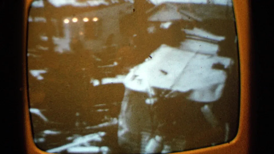 1965 Minnesota 8mm frame showing a person amid storm debris beside a white vehicle or large damaged object.