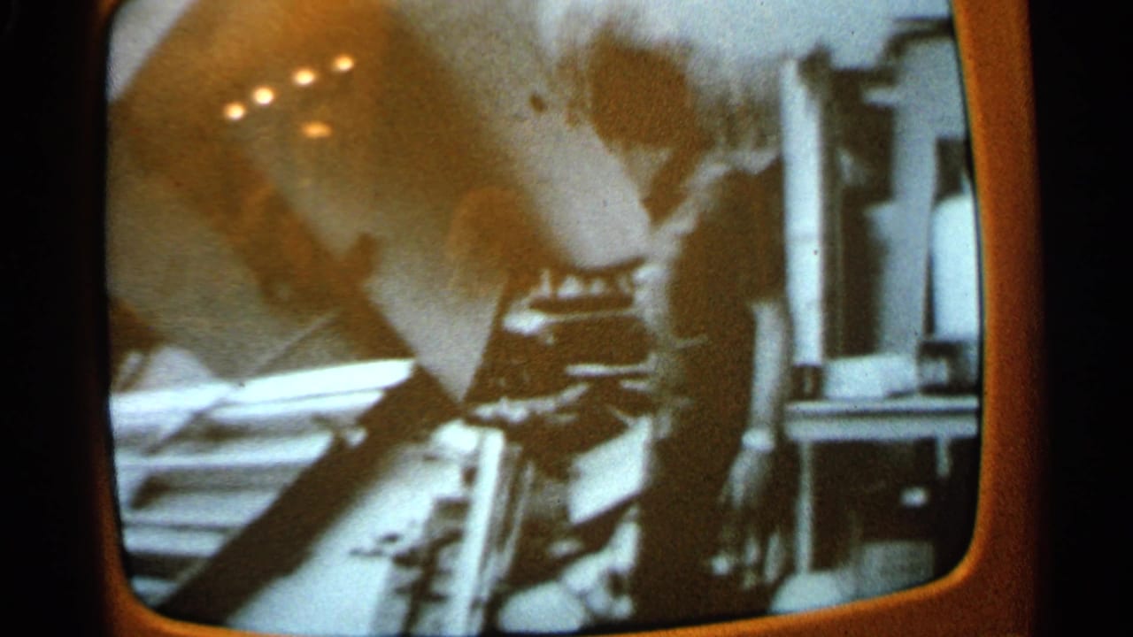 Close view of a television broadcast with an indistinct person and objects near the screen edge.