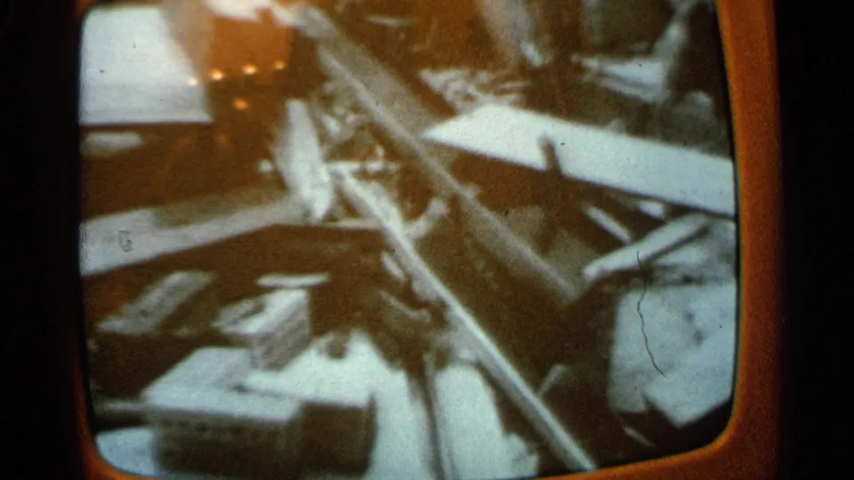 1965 Minnesota 8mm frame showing televised wreckage with debris and an indistinct figure visible in the broadcast image.