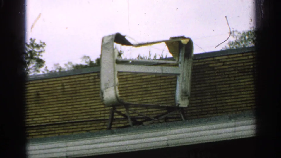 1965 Minnesota 8mm frame showing the damaged rooftop object from a closer handheld angle.