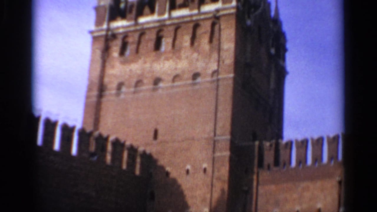 1965 Moscow frame with a red brick Kremlin tower rising above a crenellated wall against blue sky.