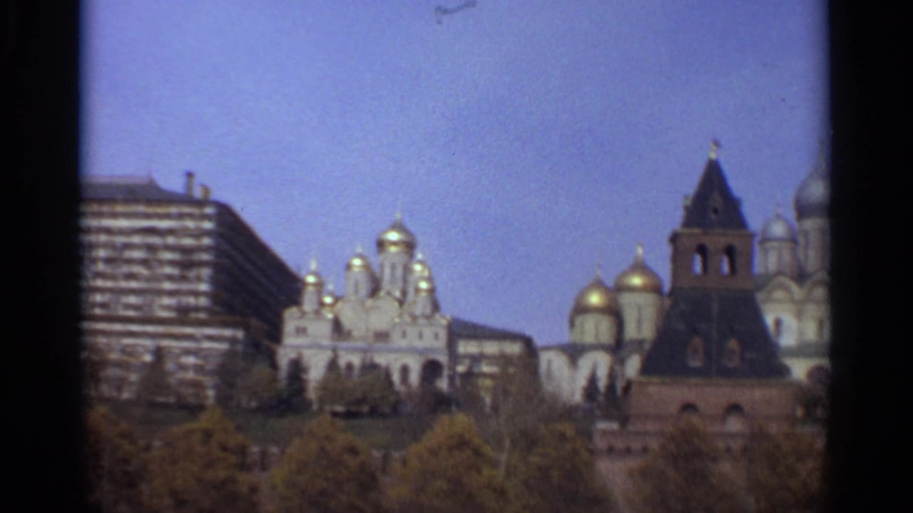 Distant Moscow landmark view with cathedral domes, a dark-roofed tower, trees, and a modern high-rise.